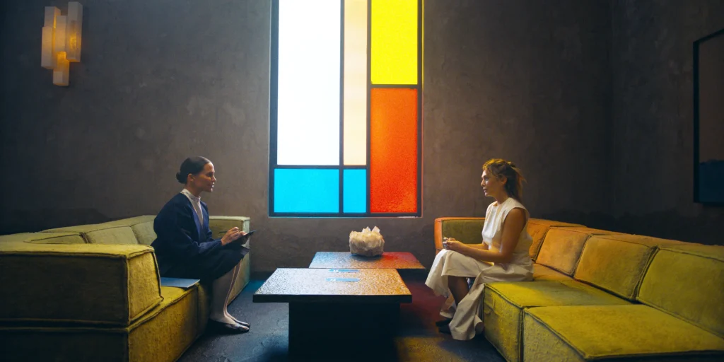 alicia vikander and elizabeth olsen sitting opposite each other in trailer for the assessment film