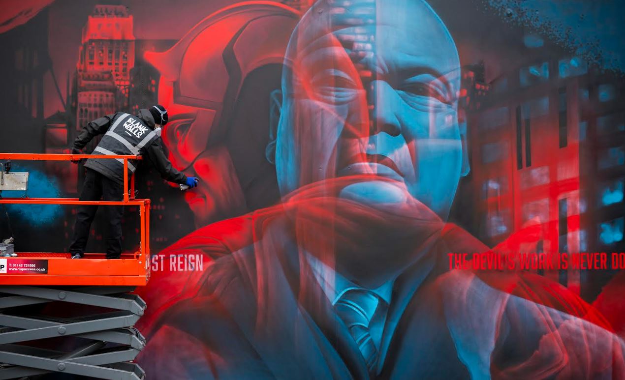 Blue and Red Comic Book superhero mural. You can see both hero and villain, as well as the artist on a mini-crane.